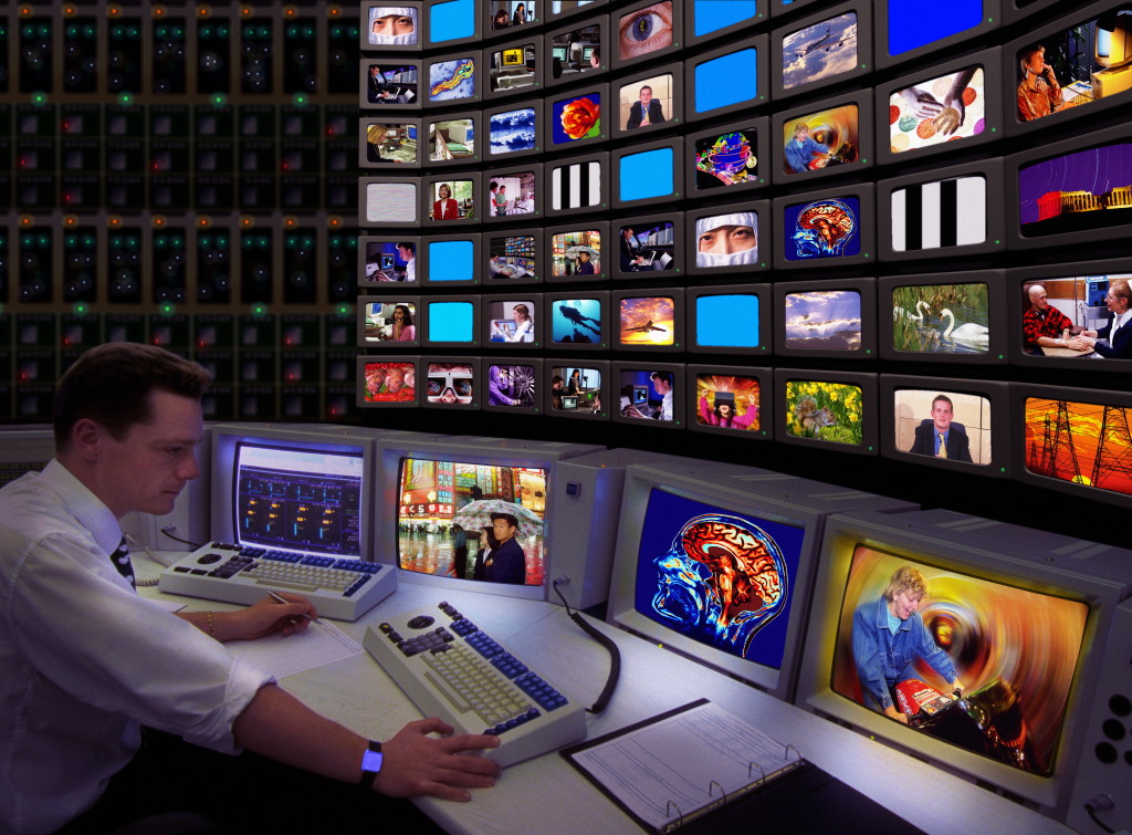 MODEL RELEASED. Television control room. Conceptual composite image of a technician monitoring the output from a television station.