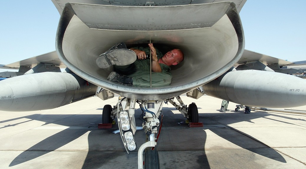 Een grondwerktuigkundige van de Koninklijke Luchtmacht inspecteert de luchtinlaat van een F-16.